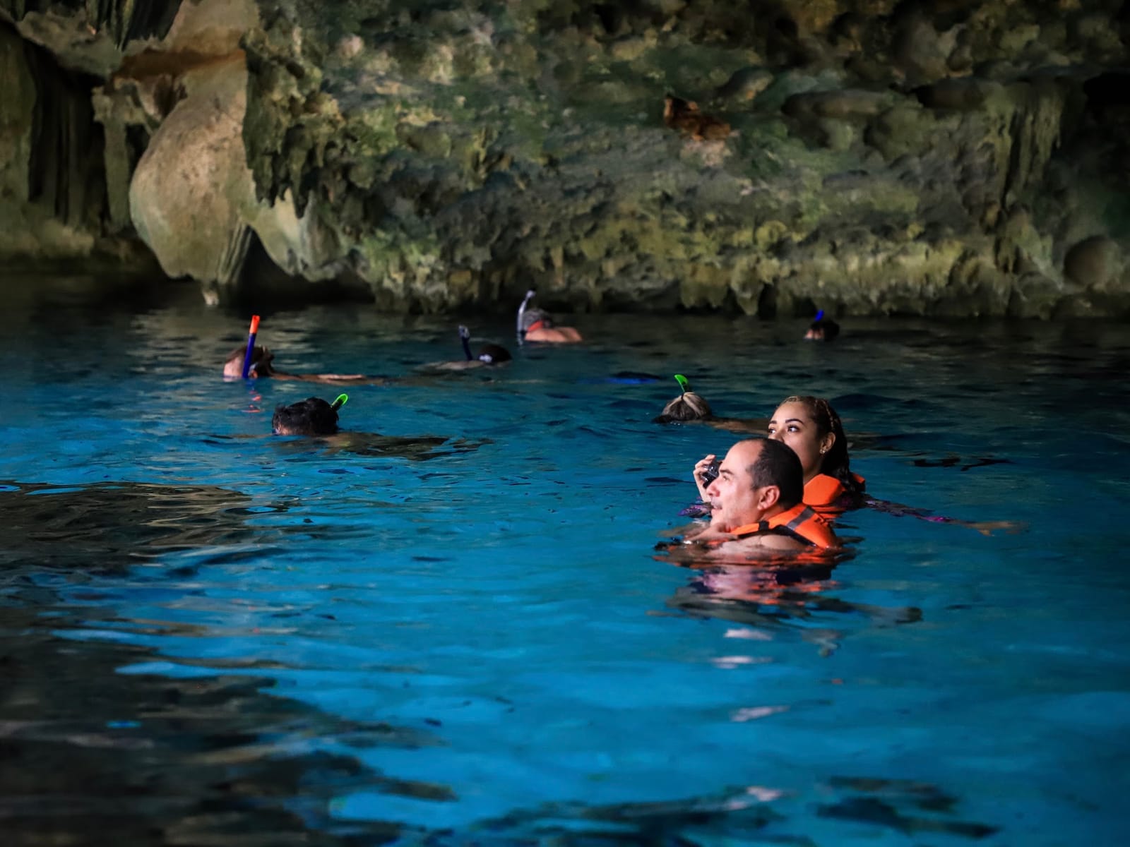 Visitantes con chaleco salvavidas haciendo snorkel en el Cenote Dos Ojos