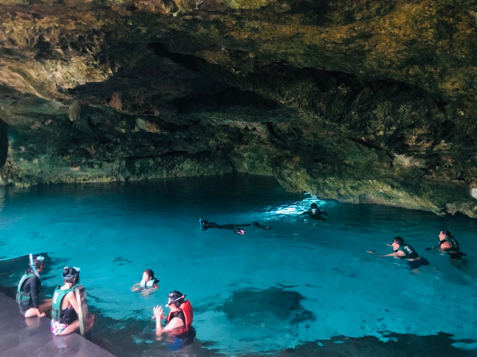 Schnorchler mit Schwimmweste im türkisfarbenen Wasser des Cenote Dos Ojos