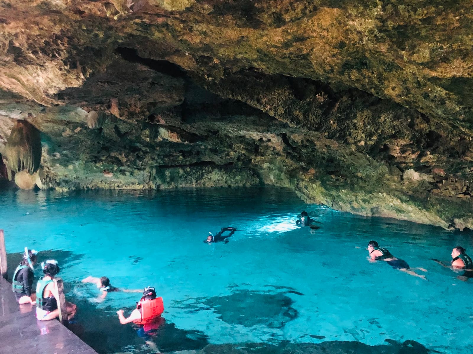 Grupo haciendo snorkel en el agua turquesa del Cenote Dos Ojos, bajo la bóveda de la caverna