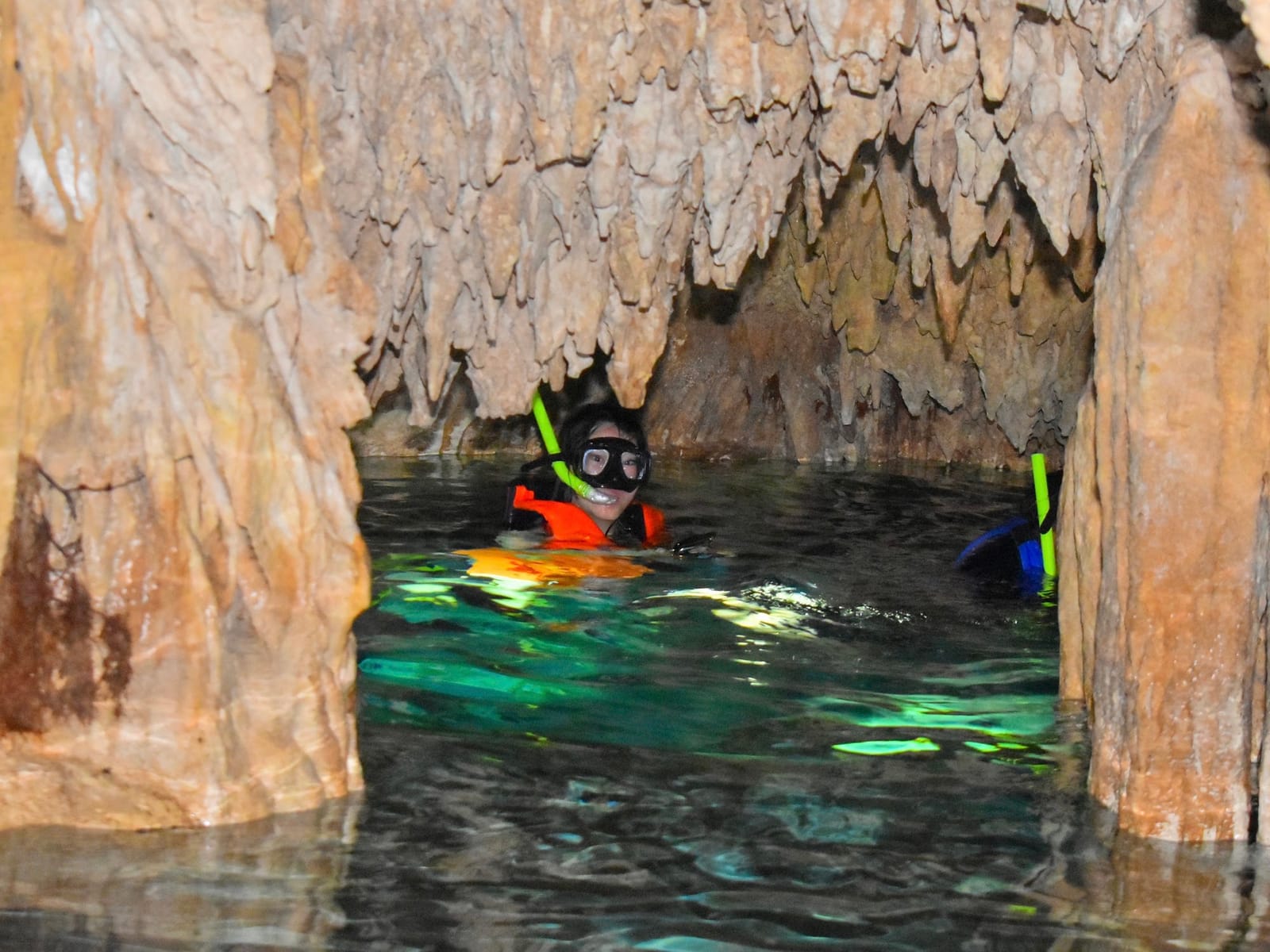 Nadador con visor y chaleco en un pasaje estrecho entre estalactitas de las cavernas de Dos Ojos