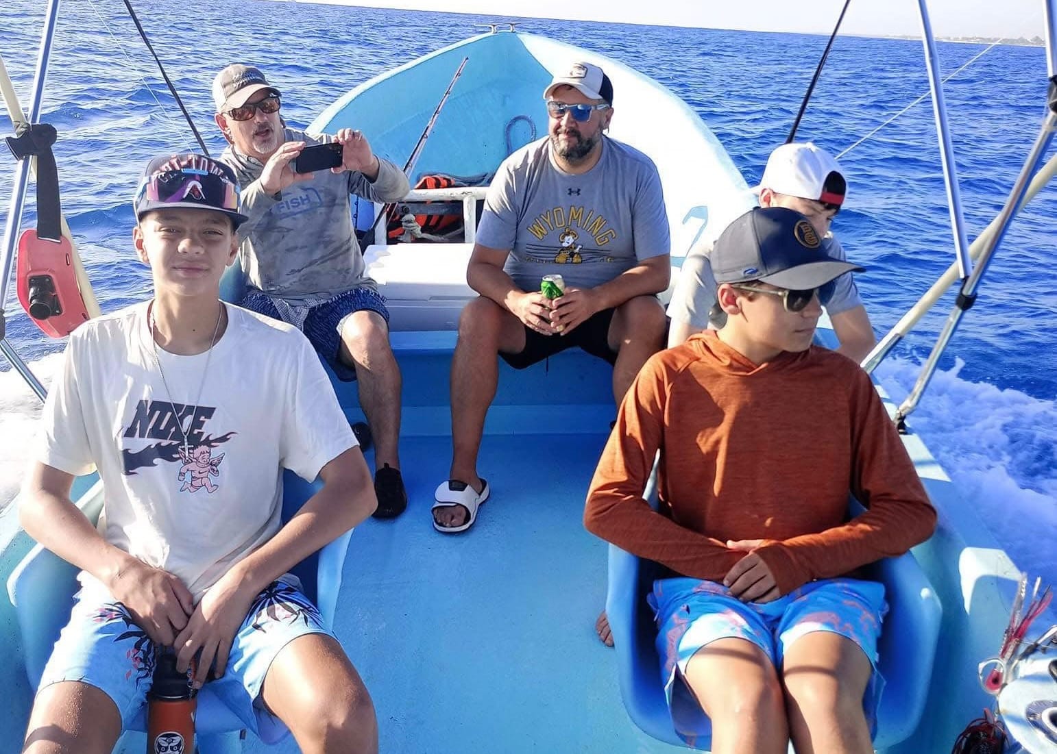 Familia con adolescentes sentada en la lancha de pesca en alta mar