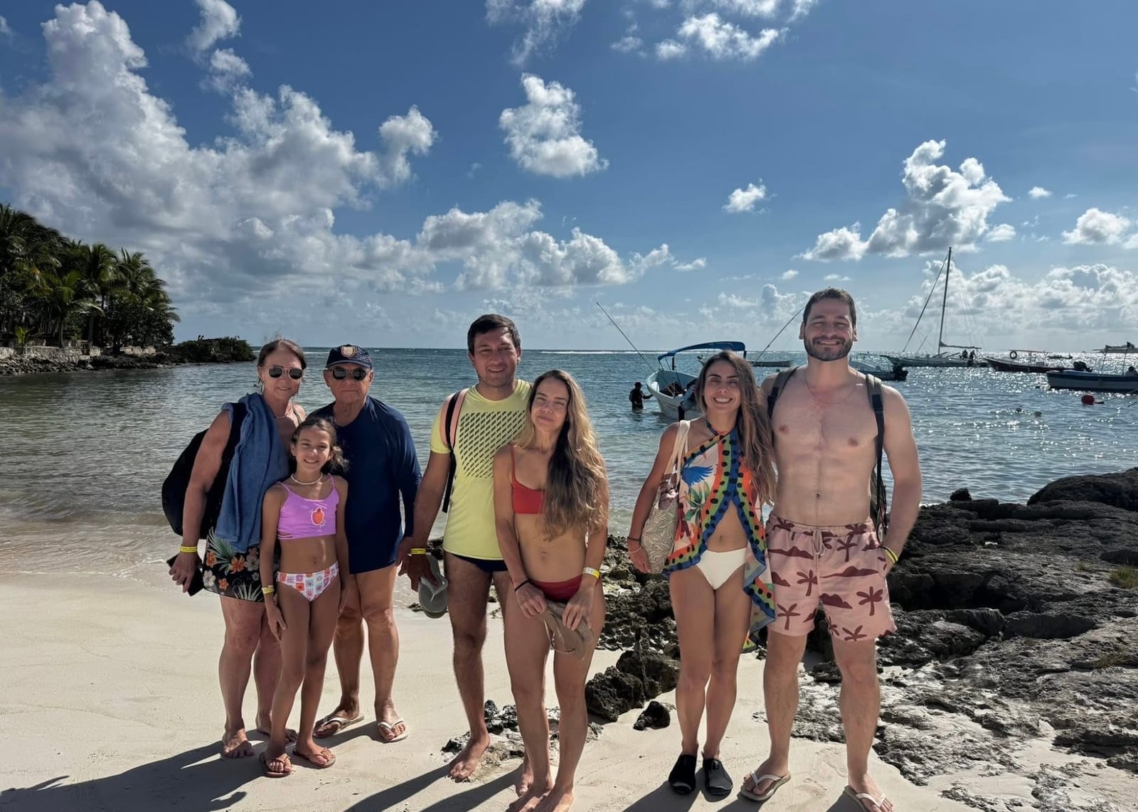 Grupo de clientes en la playa con las lanchas al fondo