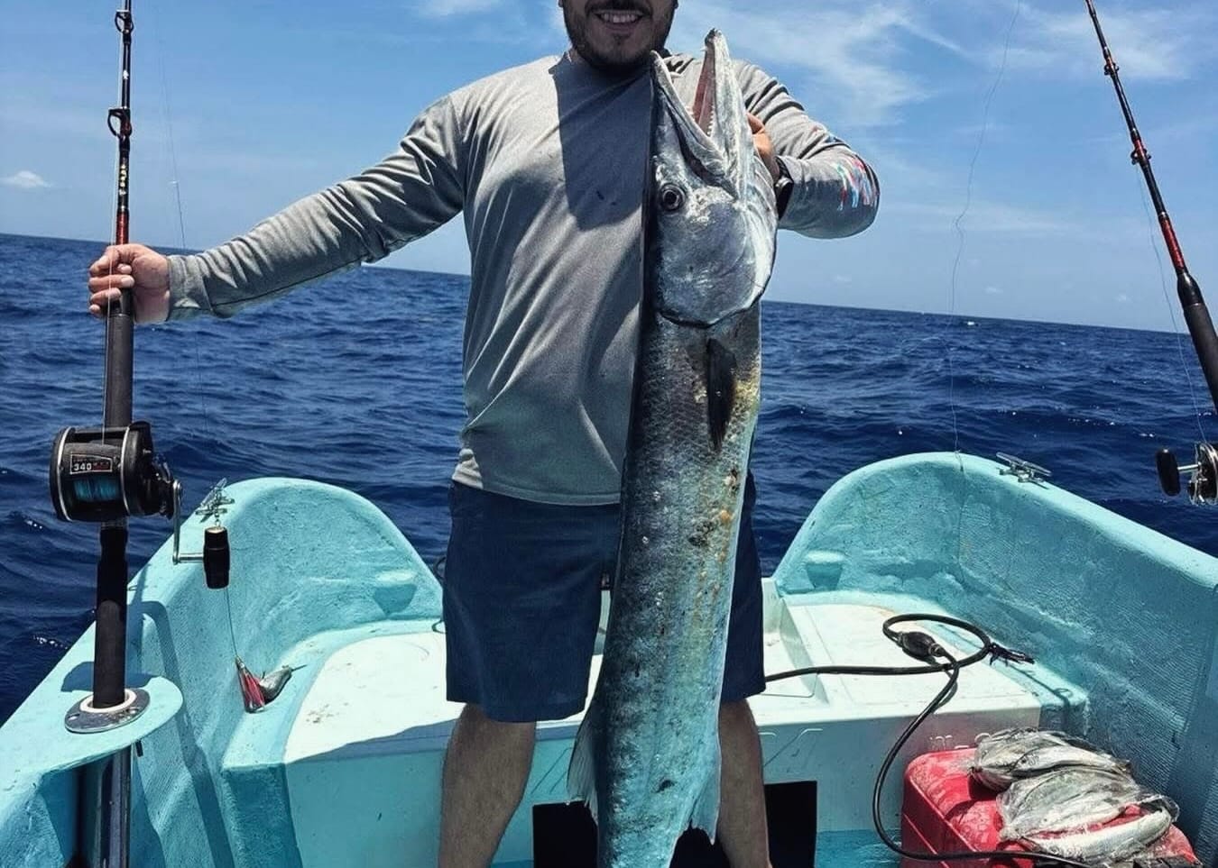 Pescador de pie en la lancha con un pez largo recién capturado