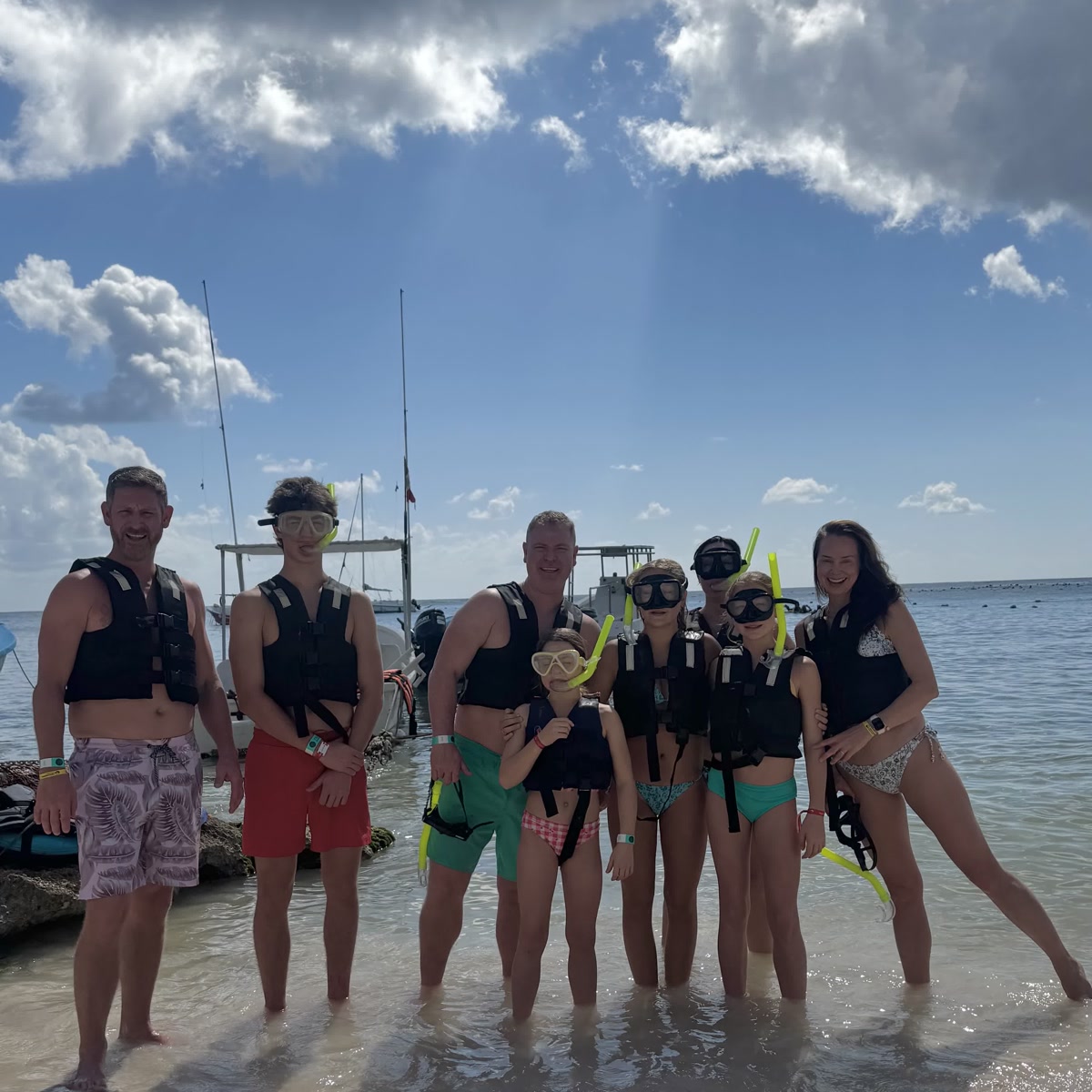 Familia con máscaras de snorkel y chalecos en la playa de Akumal Bay