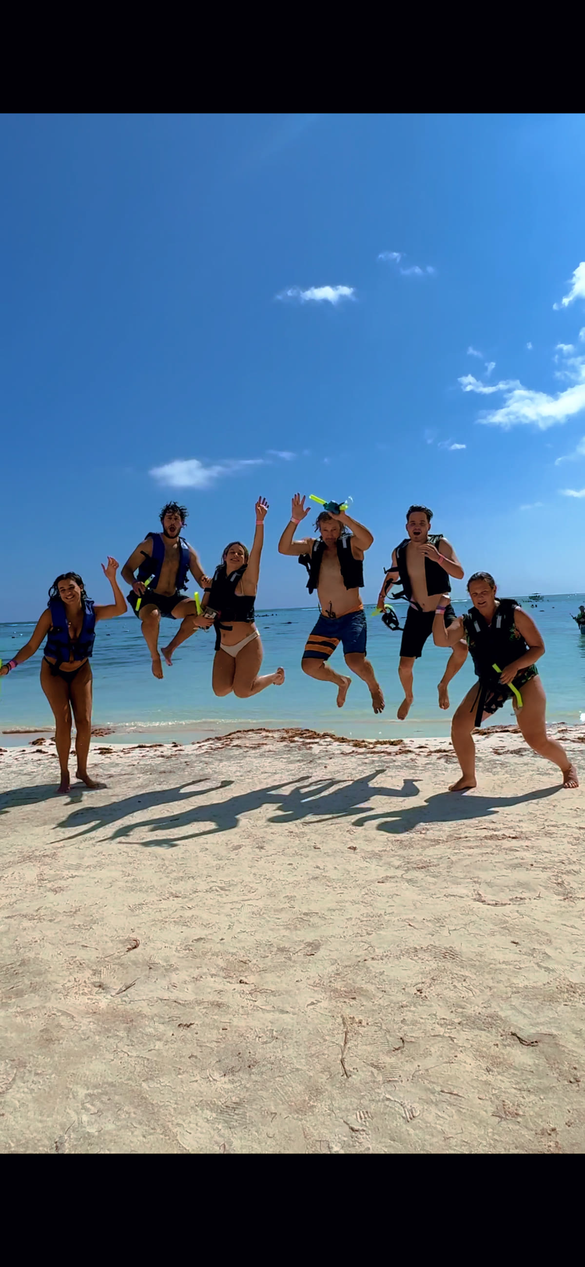 Group of snorkelers jumping into Akumal Bay with life vests
