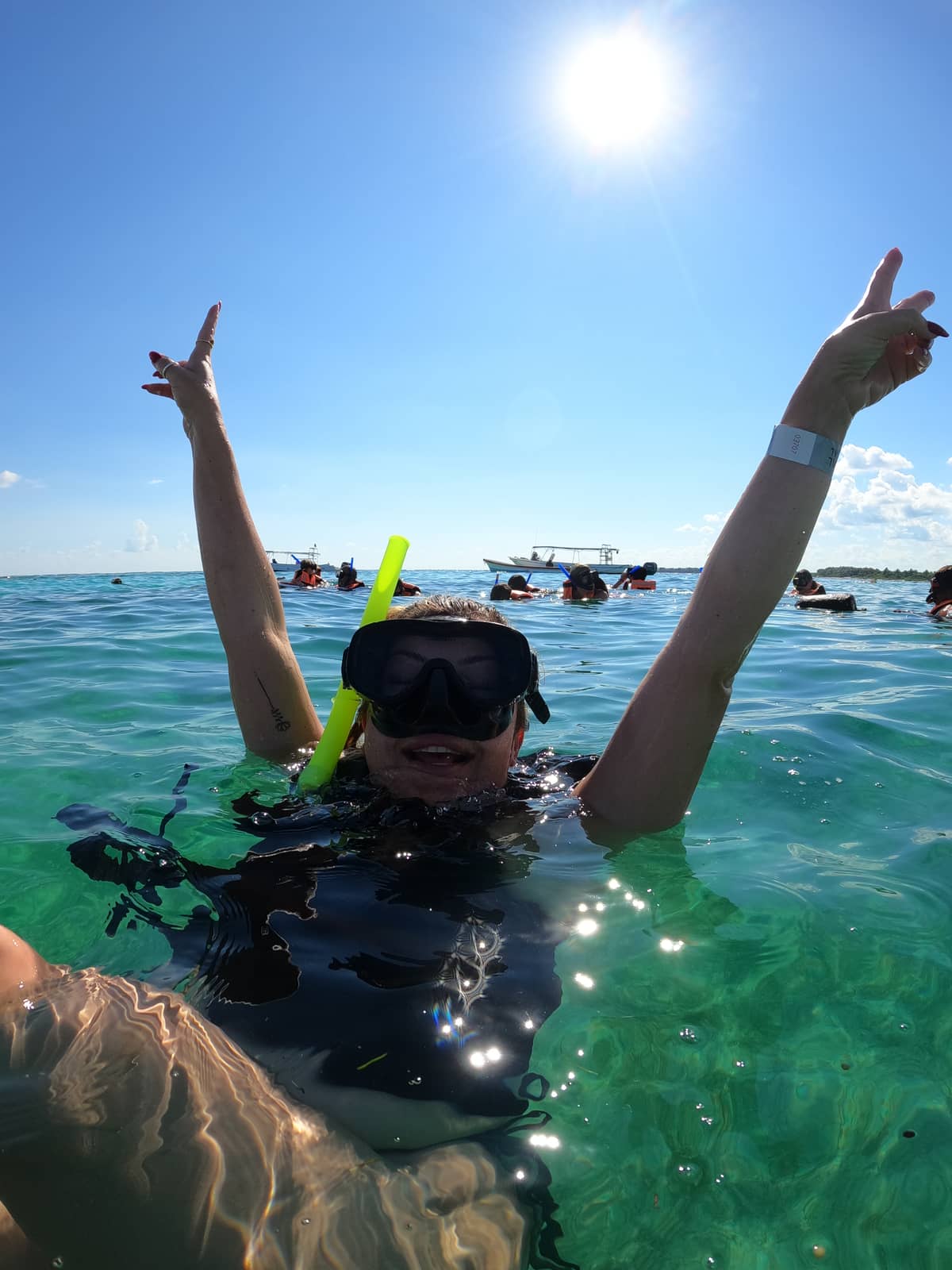 Happy snorkeler raising arms in celebration in crystal-clear Akumal Bay