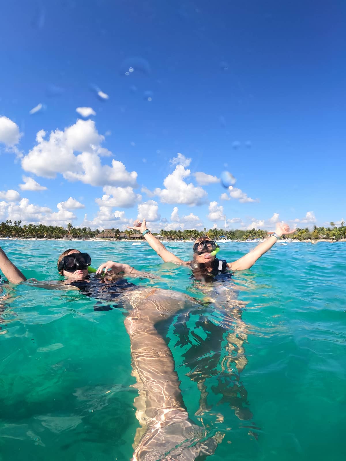 Two snorkelers with masks in turquoise water at Akumal Bay near a sea turtle