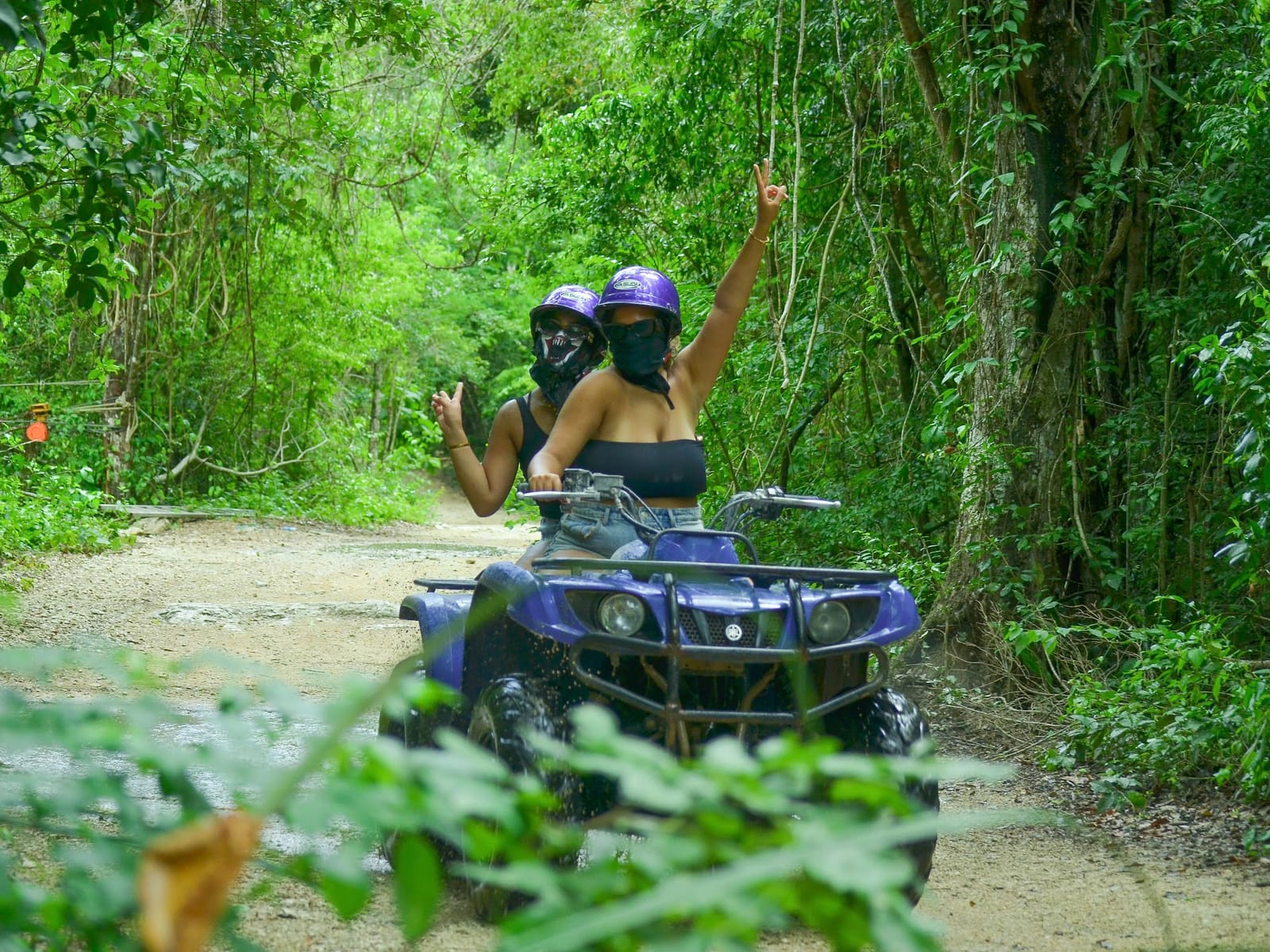 Dos personas con casco en una cuatrimoto doble por un camino de selva cerca de Akumal