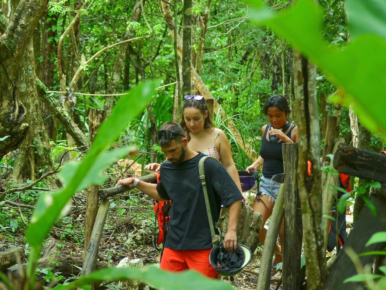 Group walking a jungle path with helmets in hand