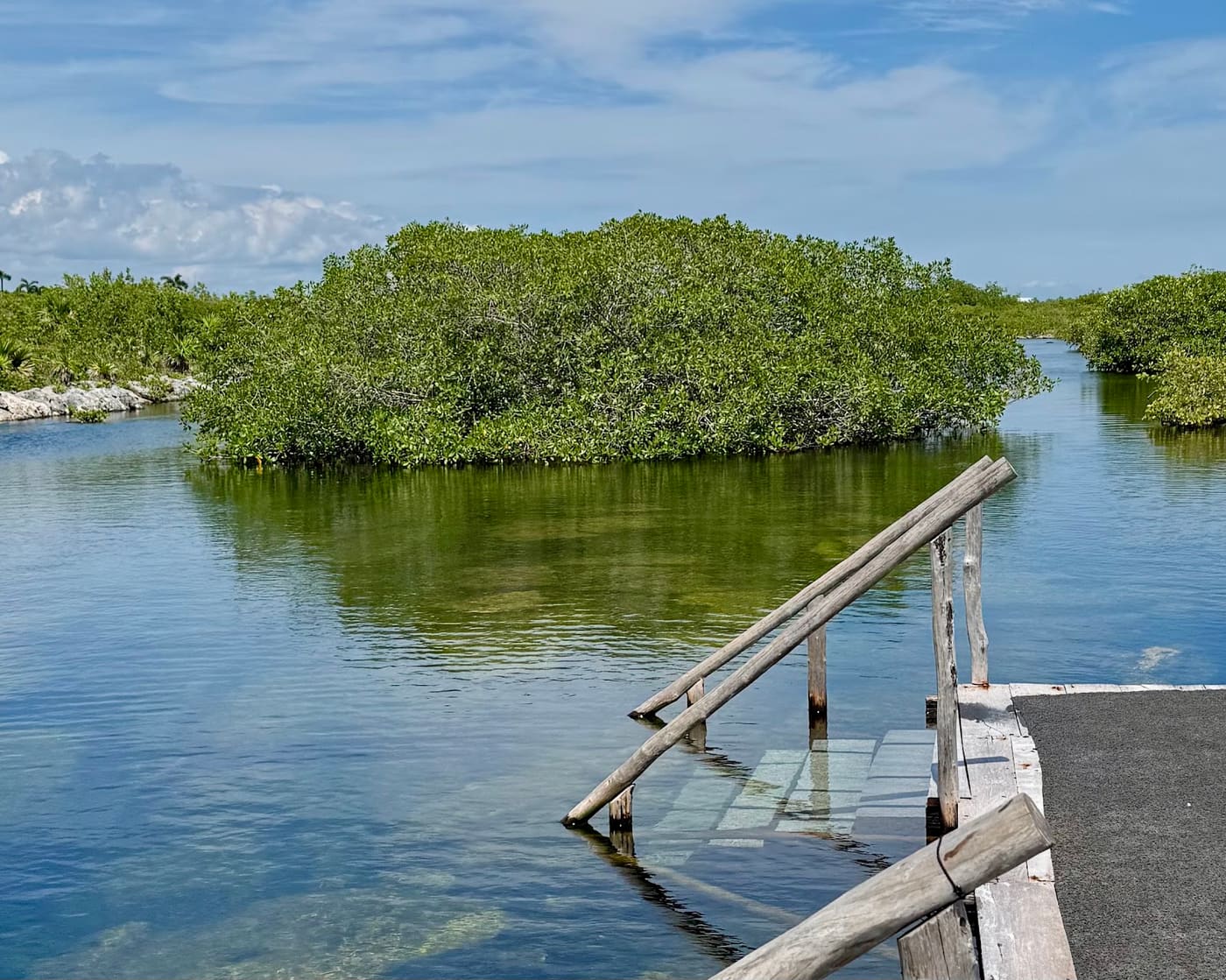 Escalera hacia el agua frente a un islote de manglar, punto de inicio del snorkel guiado en Yal-Kú